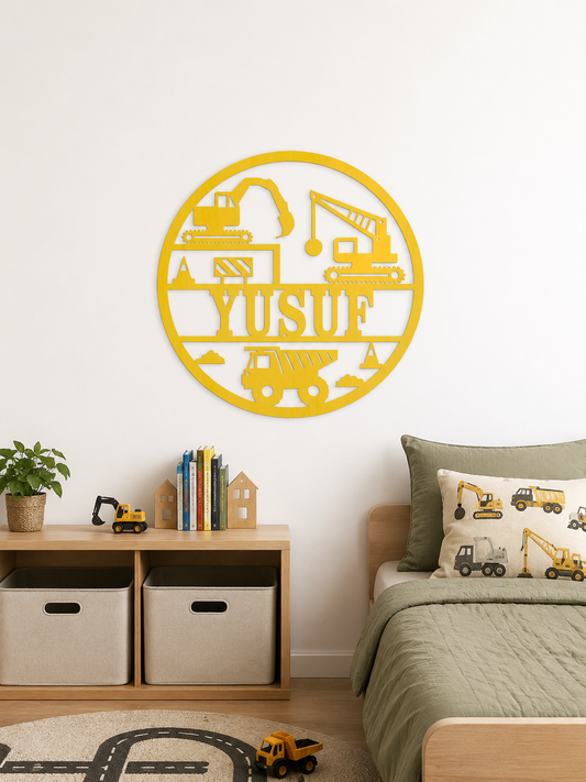 A yellow circular metal wall art piece featuring construction vehicle silhouettes and the name 'YUSUF' in the center, displayed on a white wall above a children's bed and storage shelf.