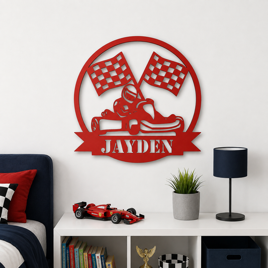 A red metal wall art piece featuring a go-kart, checkered flags, and the name 'JAYDEN' in a circular frame, displayed on a white wall above a shelf with a toy race car, books, and a lamp.